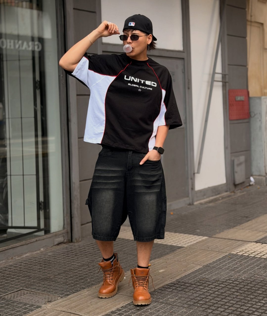 Outfit completo On Style: remera boxy negra y blanca, gorra y bermuda baggy de jean negra con botas color miel